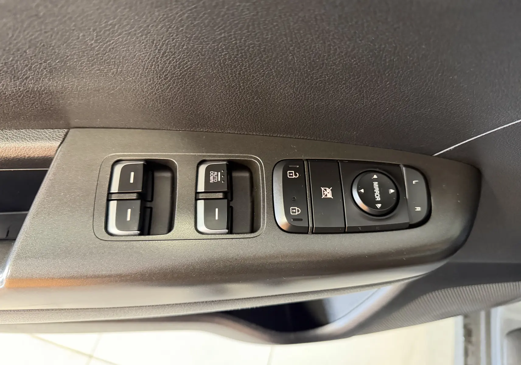 Commande des vitres et rétroviseurs côté conducteur d’un KIA SPORTAGE gris 2019, vue rapprochée intérieure.