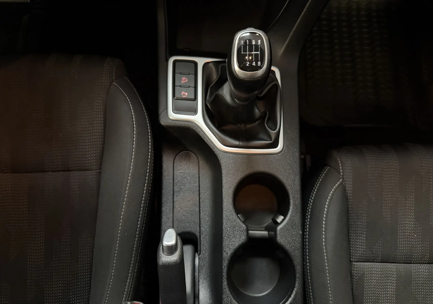 Vue plongeante sur la console centrale du Kia Sportage gris 2019, mettant en valeur le levier de vitesse manuel et les sièges avant.