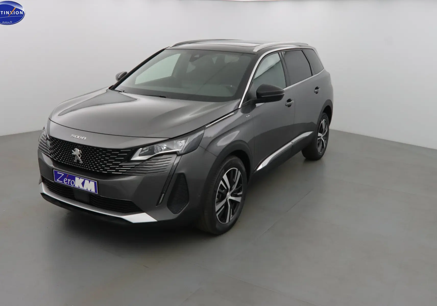 Peugeot 5008 gris platinium métal vue 3/4 avant droit, SUV moderne avec calandre noire et jantes alliage.