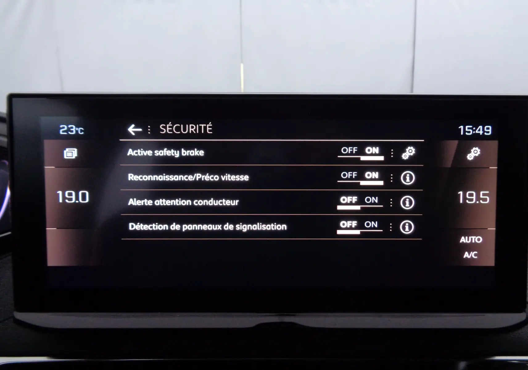 Tableau de bord numérique du Peugeot 5008 gris platinium, affichant les réglages de sécurité et la climatisation.