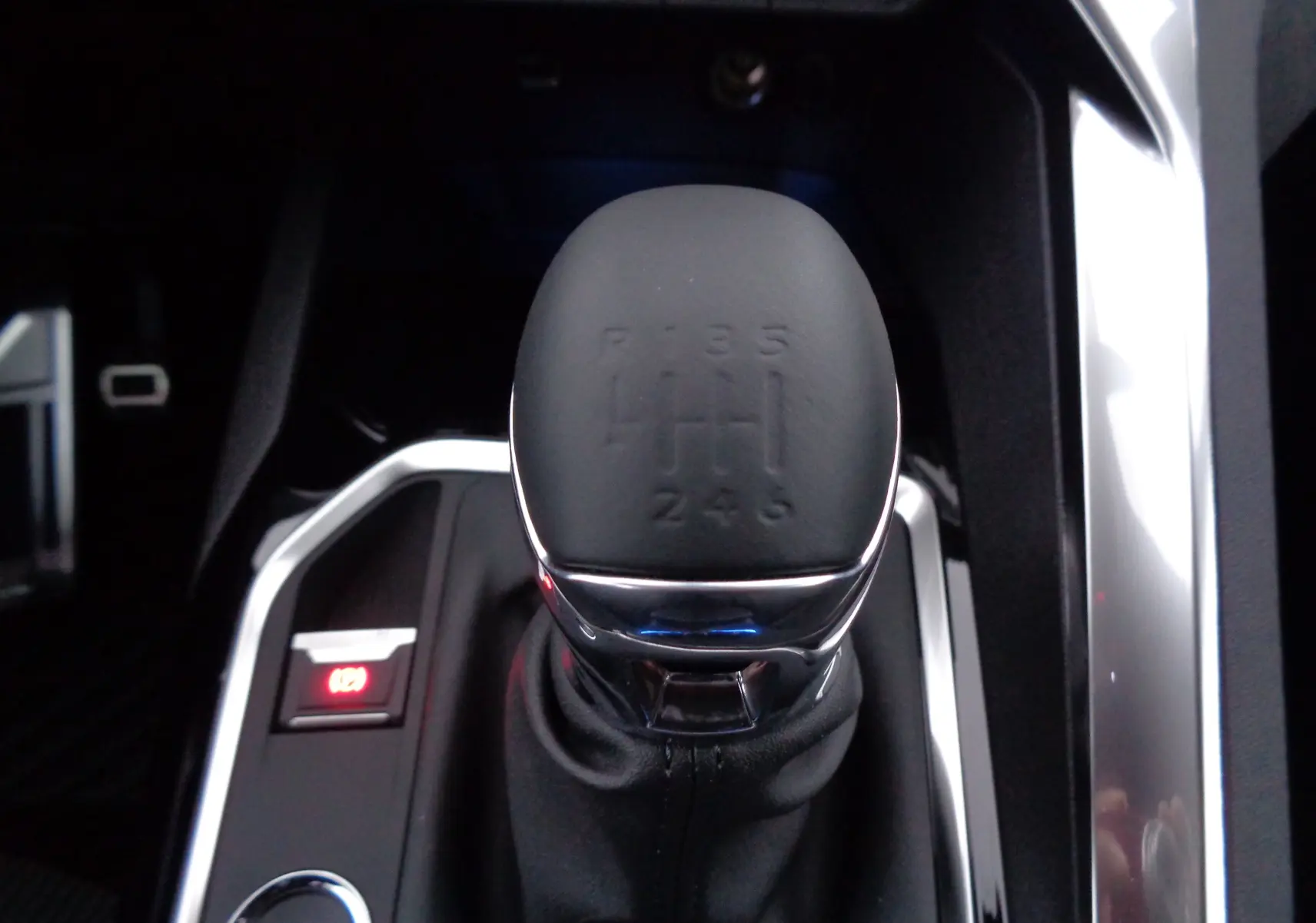 Le levier de vitesses manuel noir du Peugeot 5008 GT 2023 vu de dessus avec contour chromé et frein à main électronique.