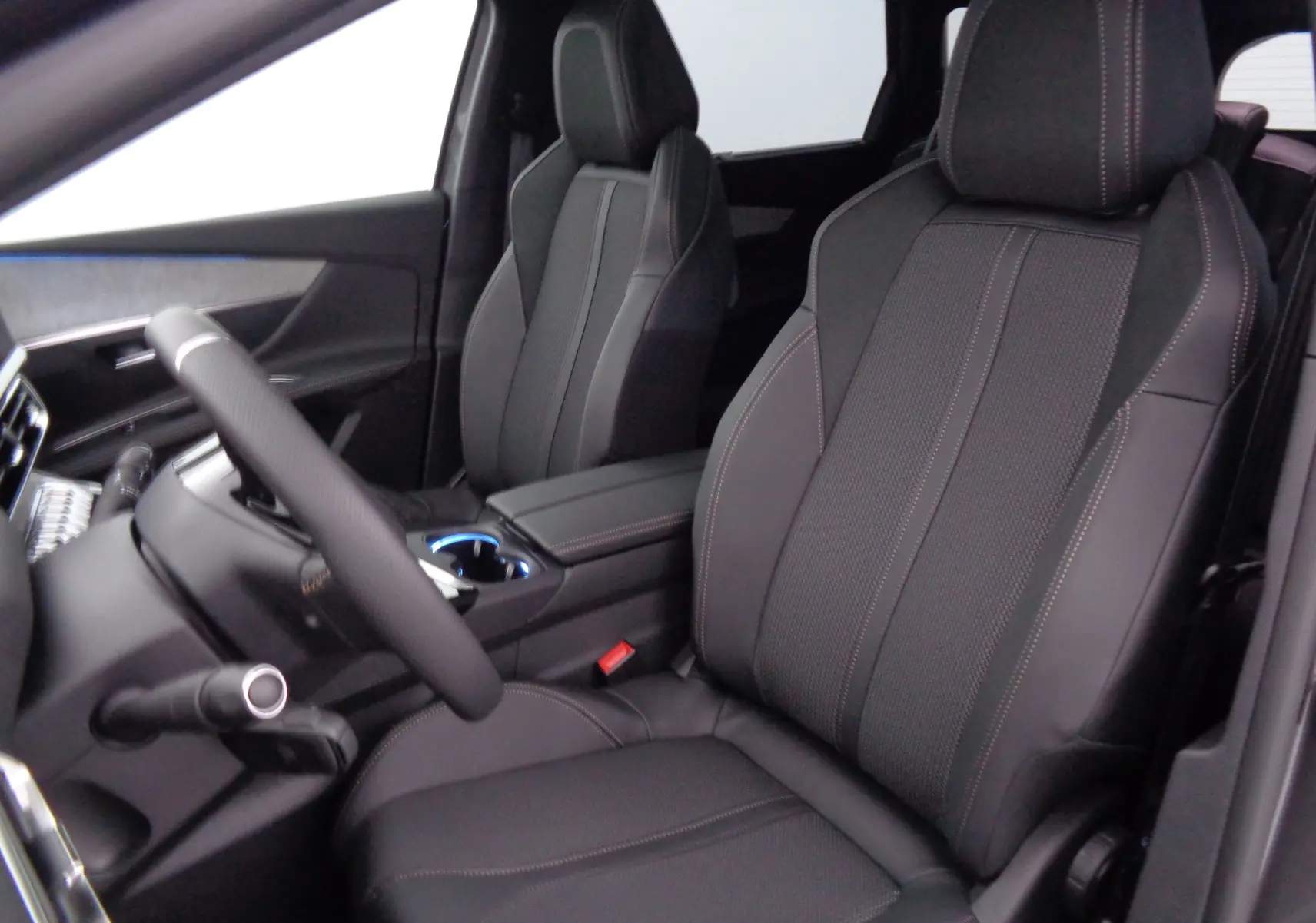 Vue intérieure du Peugeot 5008 2023, sièges avant en cuir noir avec surpiqûres contrastées, volant visible côté gauche.