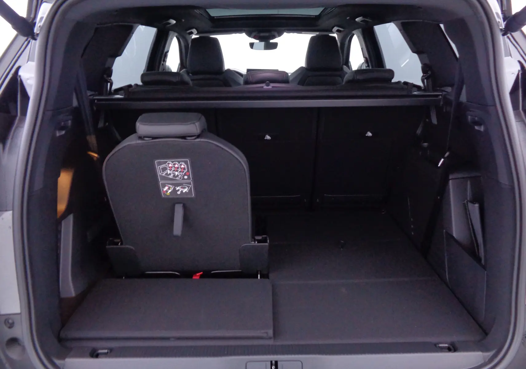 Vue arrière ouverte du coffre du Peugeot 5008 gris platinium, montrant les sièges arrière rabattables et l'espace de chargement.