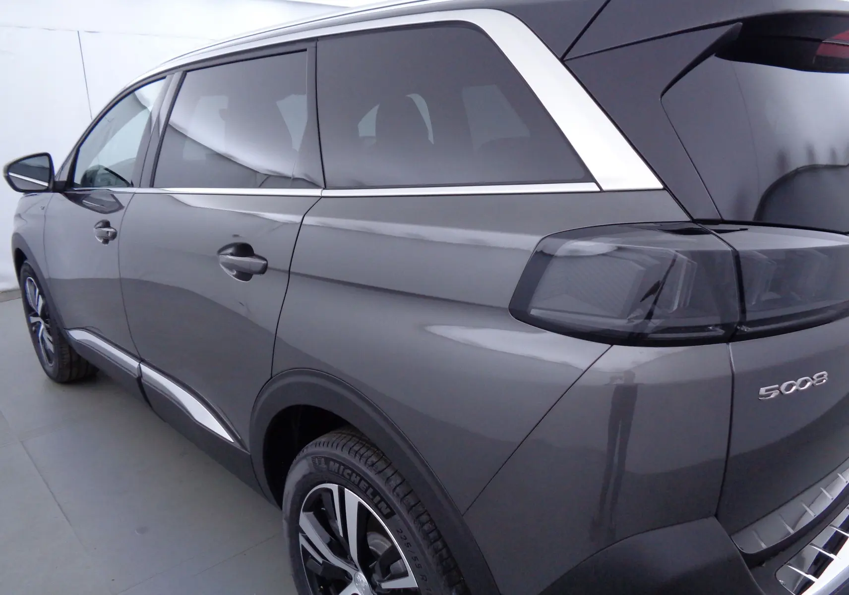 Vue 3/4 arrière côté gauche du Peugeot 5008 gris platinium métal avec feux arrière fumés et jantes alliage.