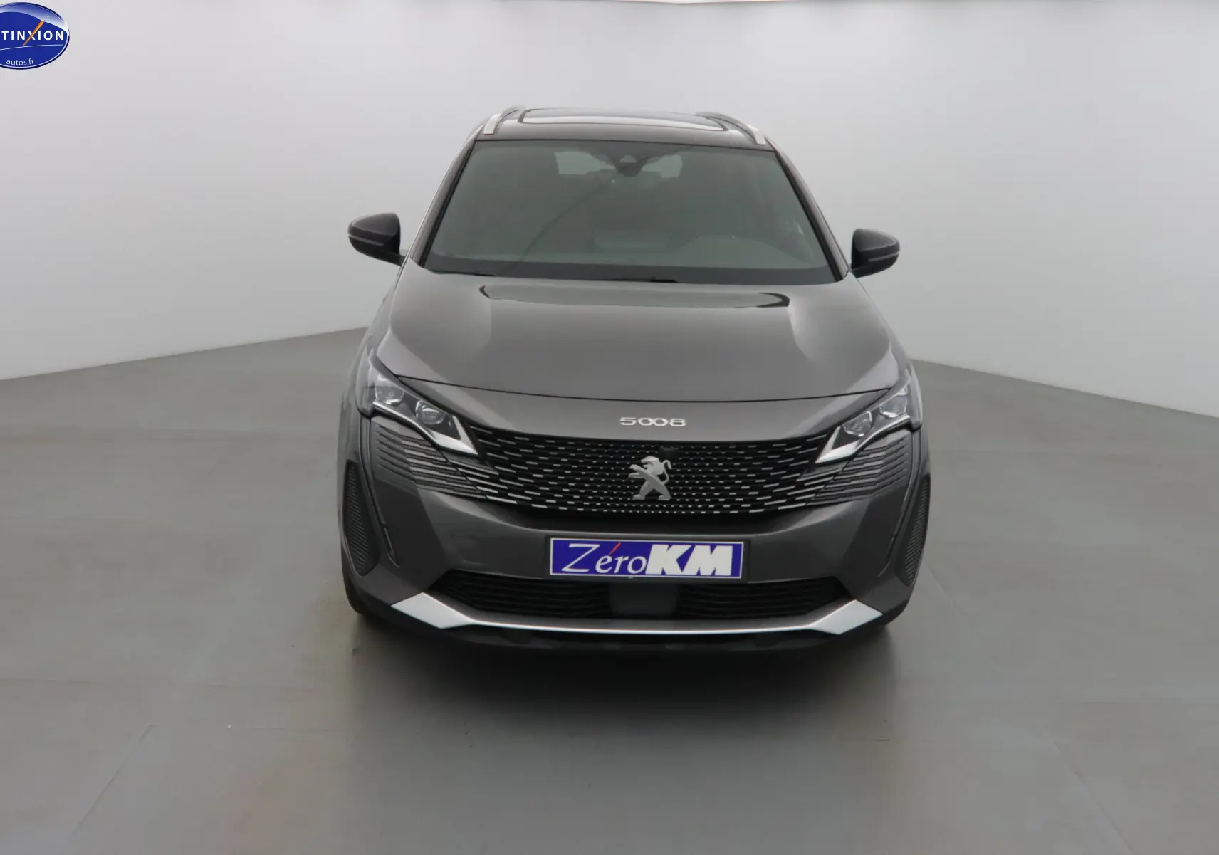 Vue frontale d'un Peugeot 5008 gris platinium métal avec calandre noire et phares LED distinctifs.