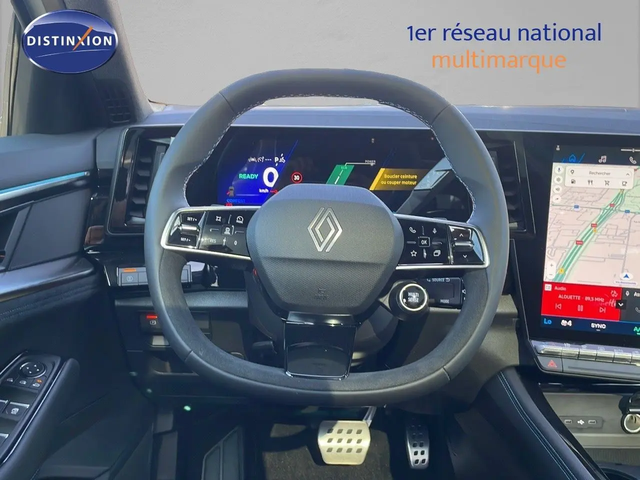 Vue intérieure centrée sur le volant Renault Espace blanc nacré 2025 avec tableau de bord numérique et écran tactile GPS.