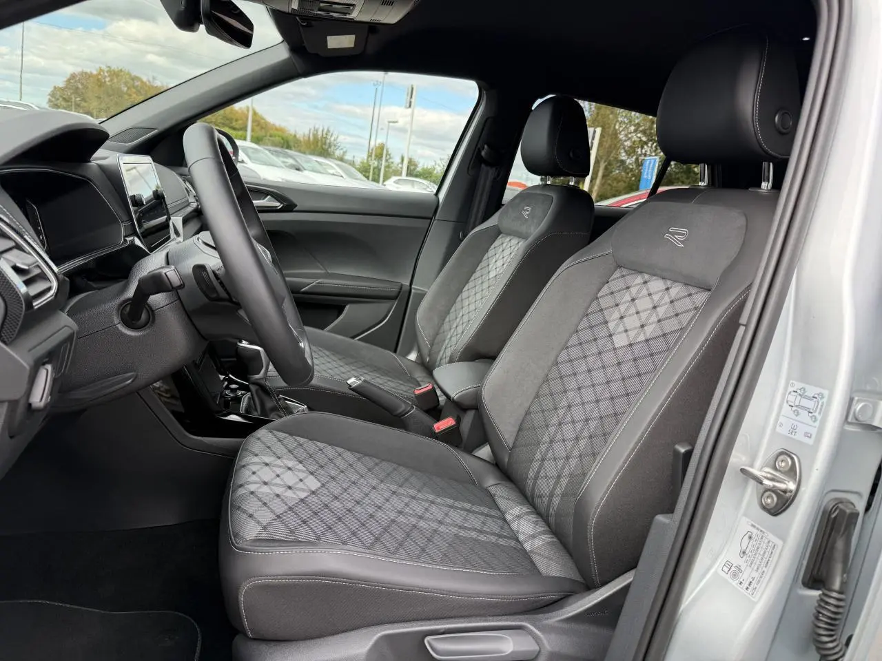Vue intérieure côté conducteur du Volkswagen T-Cross gris cendre 2025 avec sièges R-Line en tissu et alcantara.