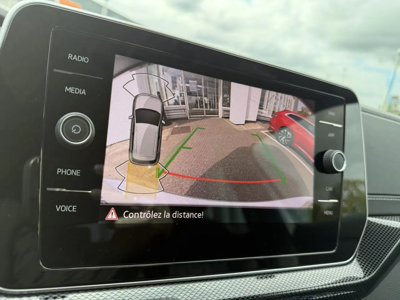 Écran de caméra de recul du Volkswagen T-Cross gris cendre montrant une vue arrière avec lignes de guidage colorées.