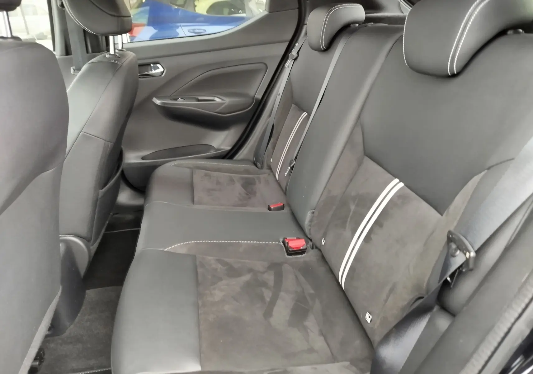 Vue latérale droite de l'intérieur arrière d'une Nissan Micra 2022, sièges noirs en cuir et alcantara avec surpiqûres blanches.