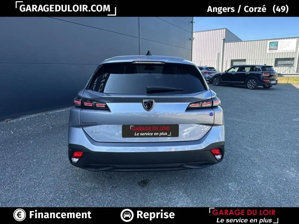 Vue arrière d'une Peugeot 308 gris clair 2023 avec feux LED et logo lion central sur un parking extérieur.