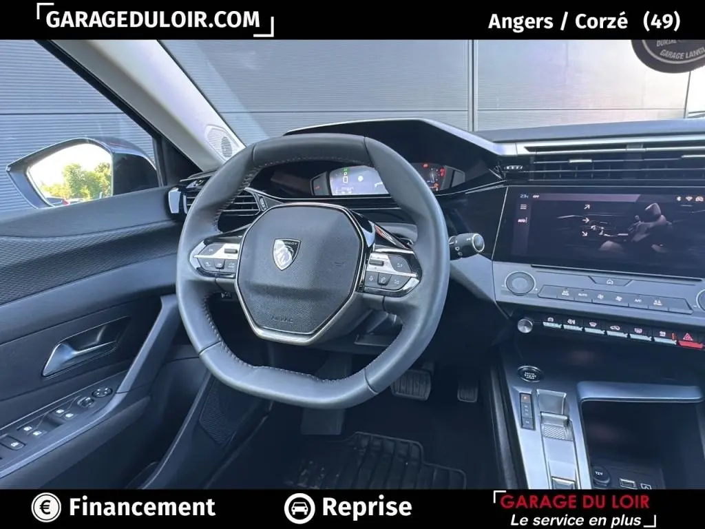 Vue intérieure du poste de conduite de la Peugeot 308 gris clair, avec volant cuir multifonctions et écran tactile central.