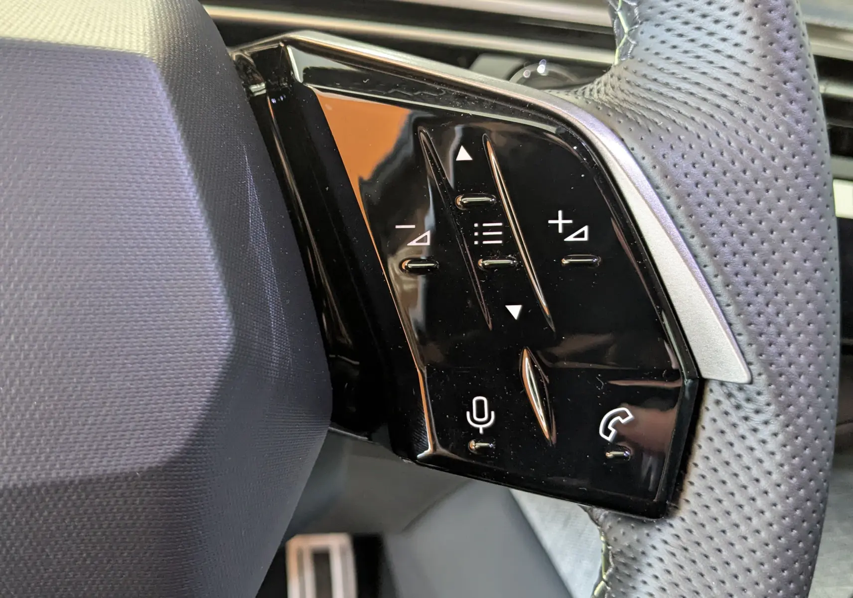 Gros plan sur les commandes tactiles noires à droite du volant perforé d’un Peugeot 3008 Bleu Ingara 2026.