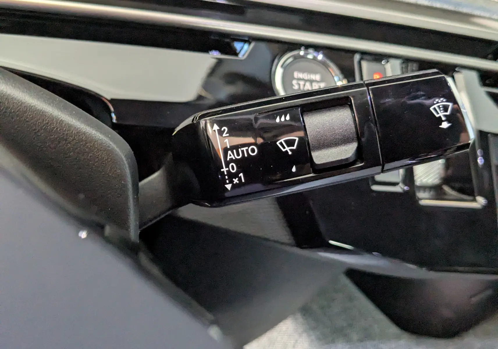Gros plan sur la commande d’essuie-glace noire dans l’habitacle du Peugeot 3008 bleu Ingaro, avec bouton Start visible.