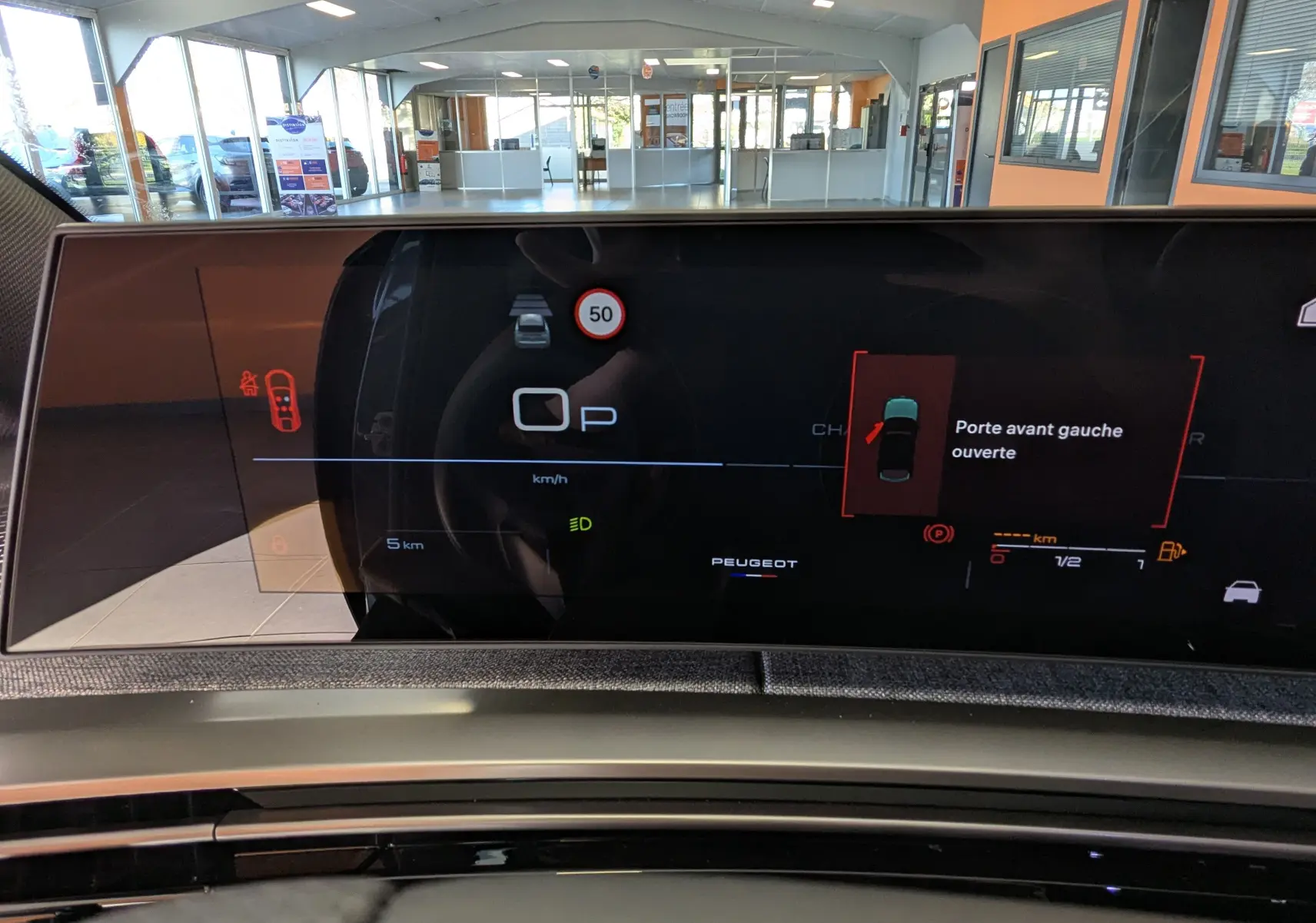 Affichage numérique du tableau de bord du Peugeot 3008 bleu Ingaro, indiquant porte avant gauche ouverte et vitesse au point mort.