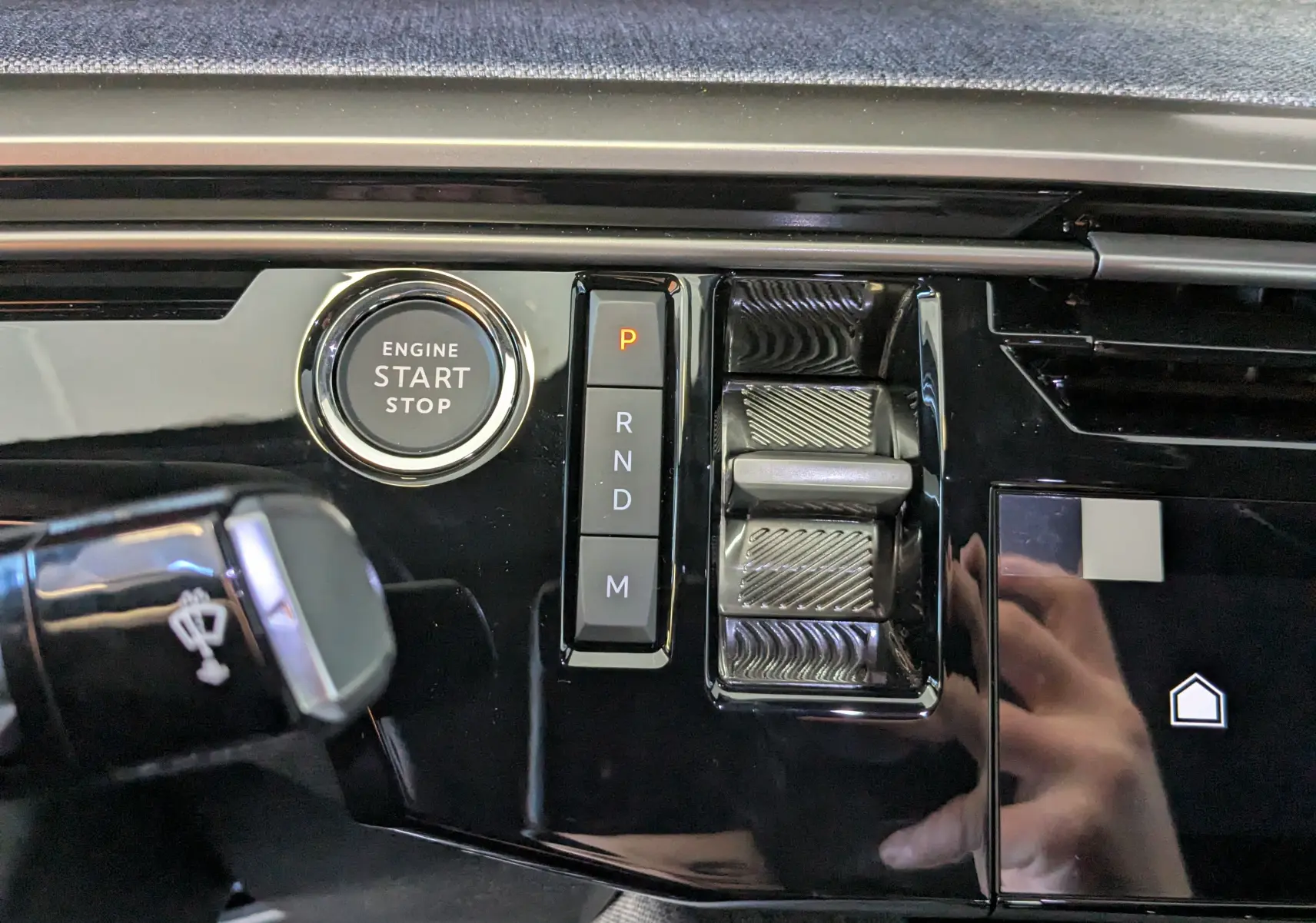 Détail intérieur du Peugeot 3008 1.2 Hybrid 145ch GT, bouton start/stop et commandes de boîte automatique sur console noire brillante.