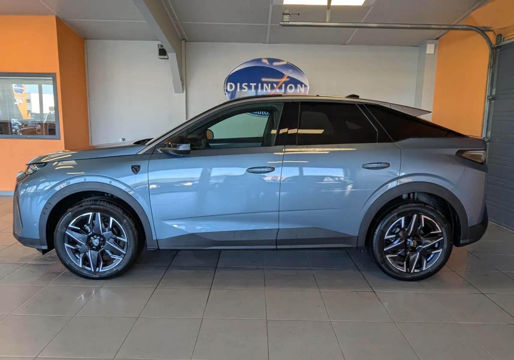 Vue latérale droite du Peugeot 3008 1.2 Hybrid 145ch GT bleu Ingaro avec jantes alliage et toit noir en intérieur showroom.