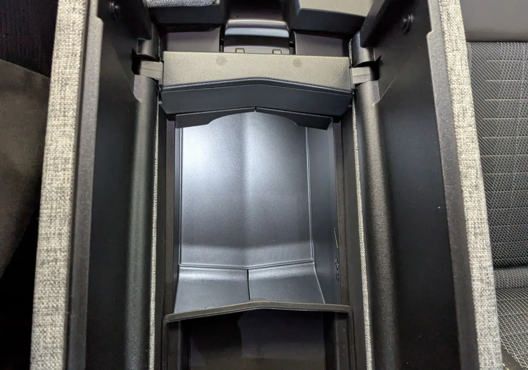 Vue plongeante sur le rangement central intérieur du Peugeot 3008 1.2 Hybrid 145ch GT, finition tissu gris.