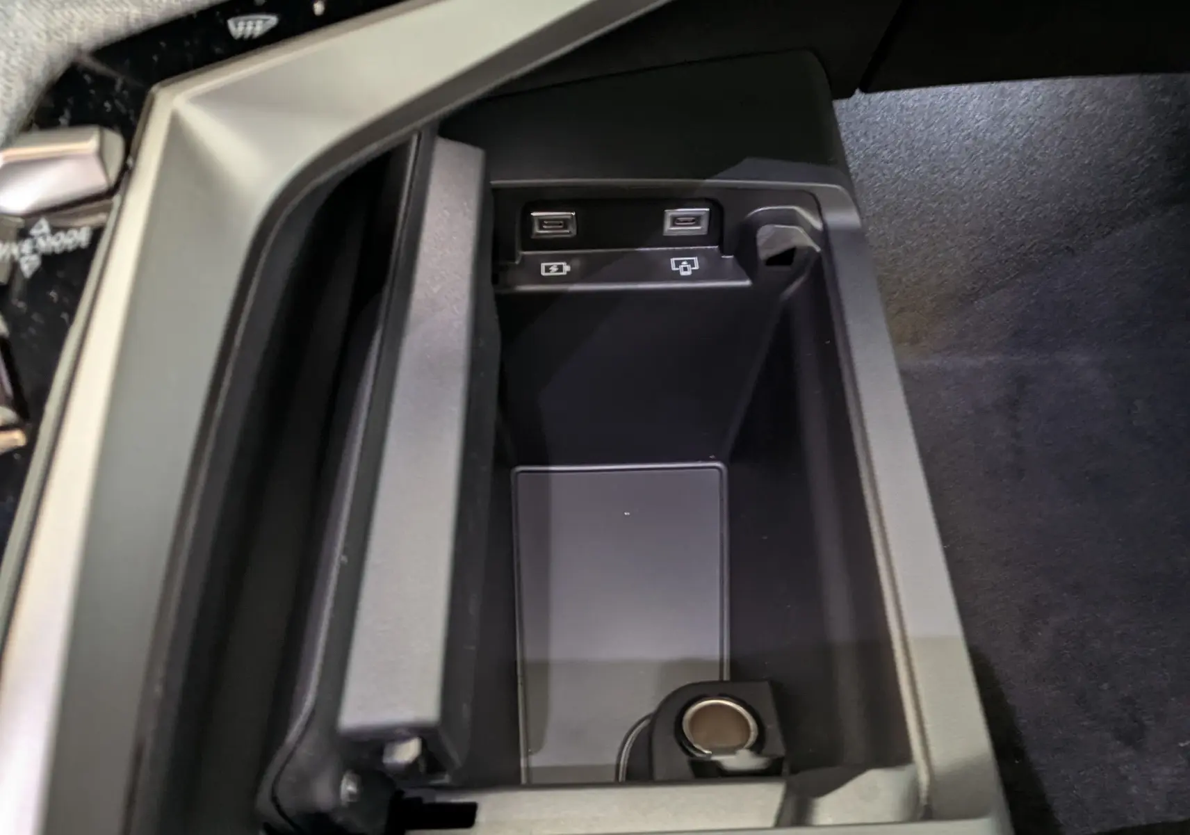 Gros plan sur le rangement central intérieur du Peugeot 3008 1.2 Hybrid 145ch GT avec ports USB et prise 12V, finition noire.