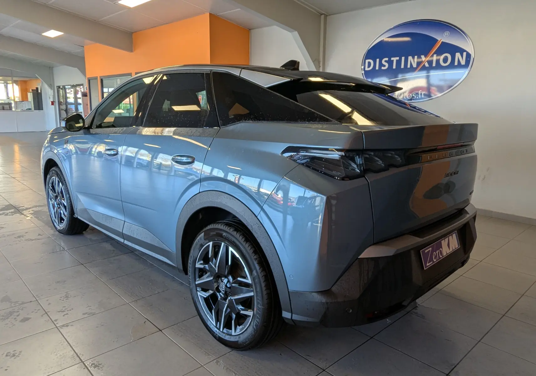 Vue 3/4 arrière droite du Peugeot 3008 hybride bleu Ingaro avec jantes noires et toit noir en intérieur showroom.