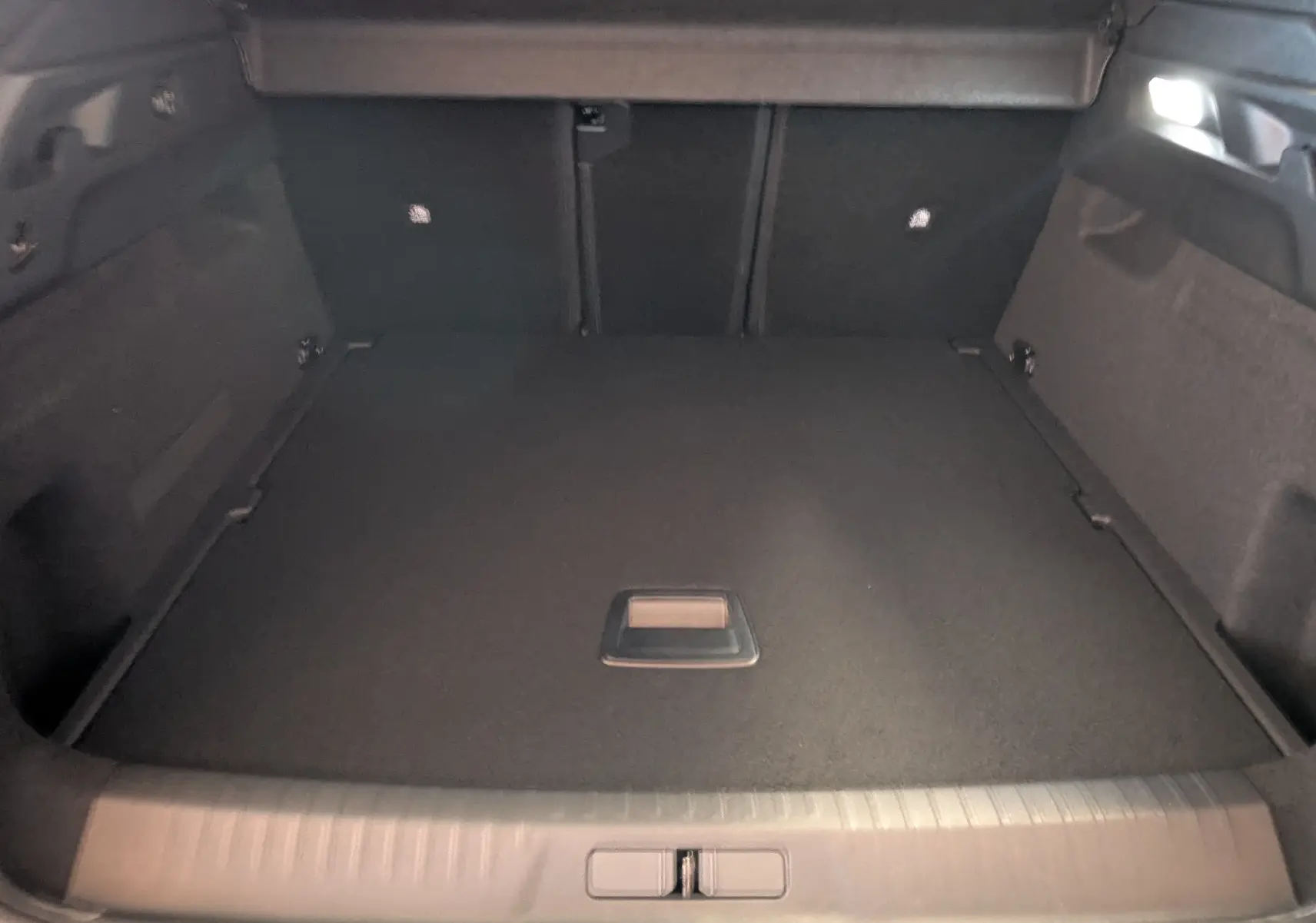 Coffre spacieux du Peugeot 3008 1.2 Hybrid 145ch GT, vue intérieure arrière avec revêtement noir uniforme.