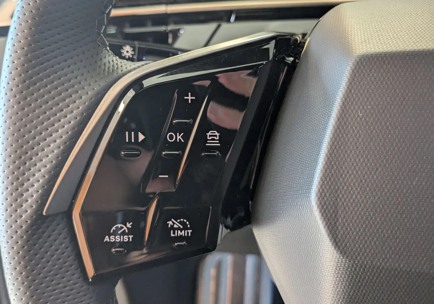 Gros plan sur les commandes multifonctions noires à gauche du volant perforé du Peugeot 3008 bleu Ingaro 2026.