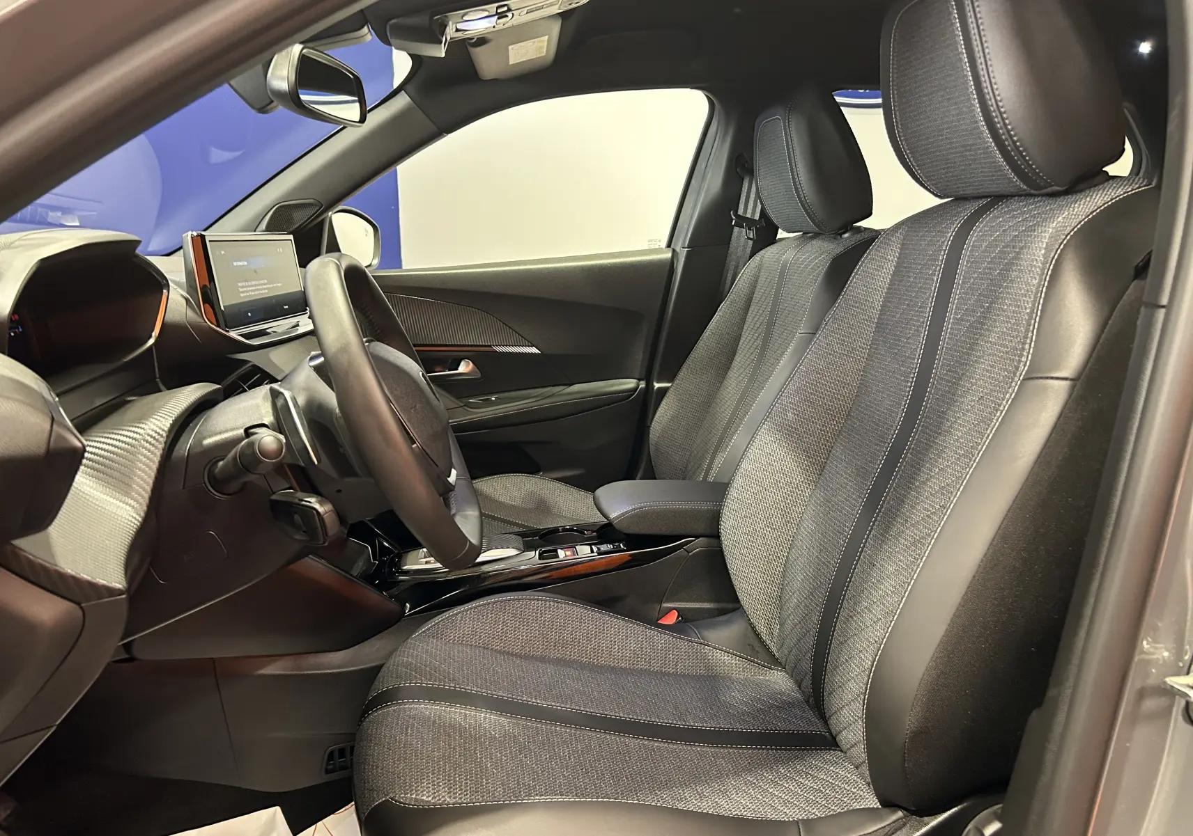 Vue intérieure côté conducteur du Peugeot 2008 gris Selenium, sièges tissu et cuir avec tableau de bord moderne.