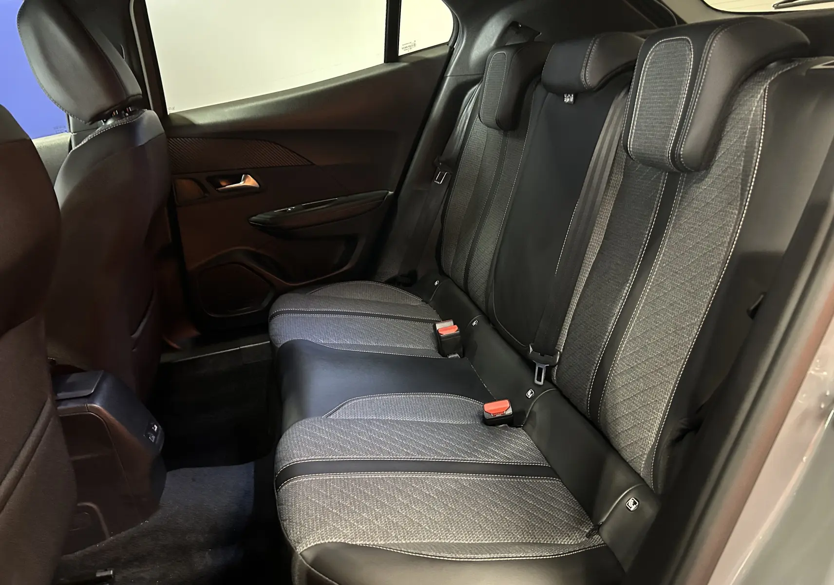 Vue intérieure côté droit des sièges arrière en tissu et cuir noir du Peugeot 2008 II Ph.2 Allure Hybrid 145 gris Selenium.