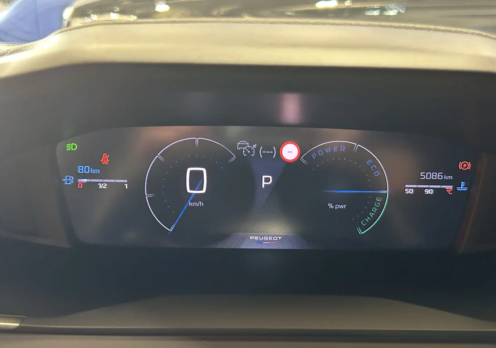 Vue rapprochée du tableau de bord numérique du Peugeot 2008 gris Selenium, affichant la vitesse à 0 km/h et 5086 km au compteur.