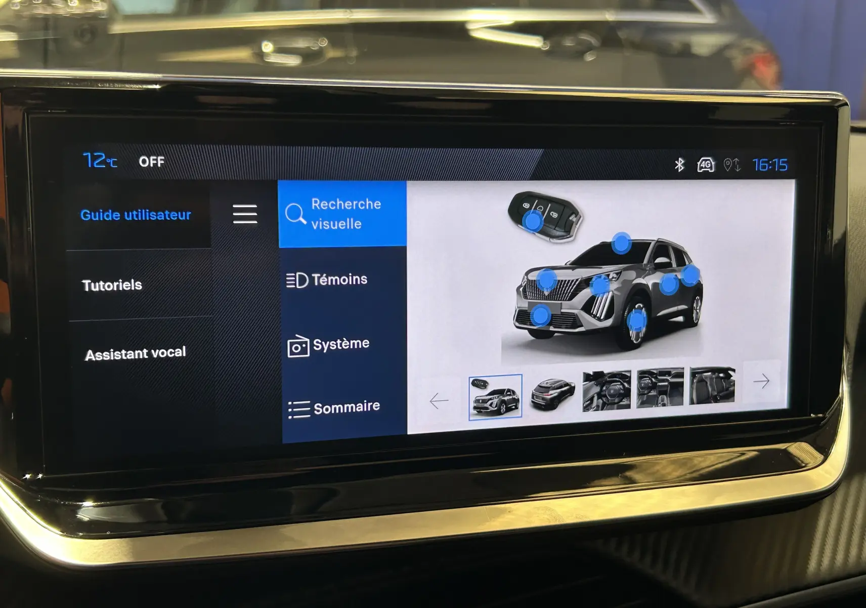 Écran tactile intérieur affichant l’aide visuelle d’un Peugeot 2008 gris Selenium, vue de face du SUV sur l’écran.