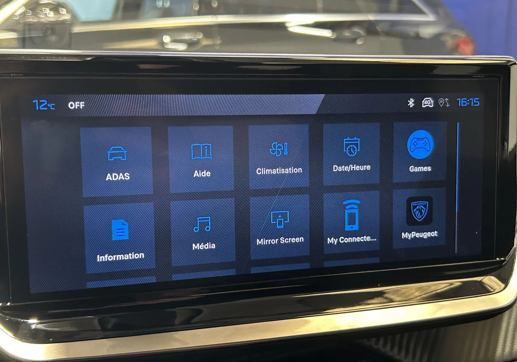 Écran tactile central du Peugeot 2008 gris Selenium, affichant le menu principal avec icônes bleues sur fond noir.