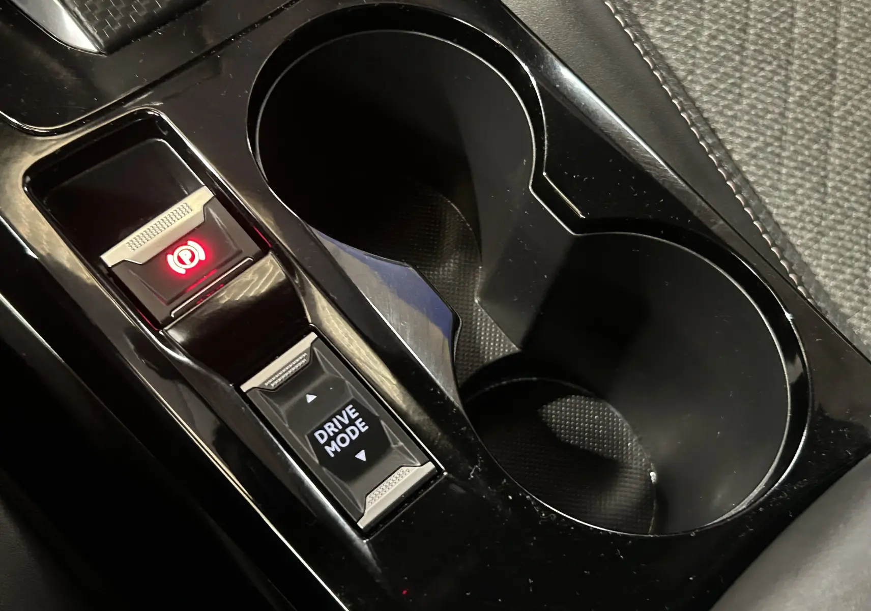 Gros plan sur la console centrale noire du Peugeot 2008 II Ph.2 Allure Hybrid avec boutons frein électrique et mode de conduite.