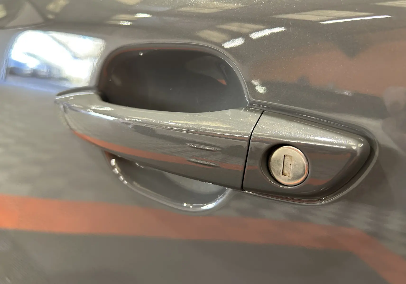 Poignée de porte avant droite gris Selenium sur Peugeot 2008 II Ph.2 Allure Hybrid 145, détail serrure mécanique visible.