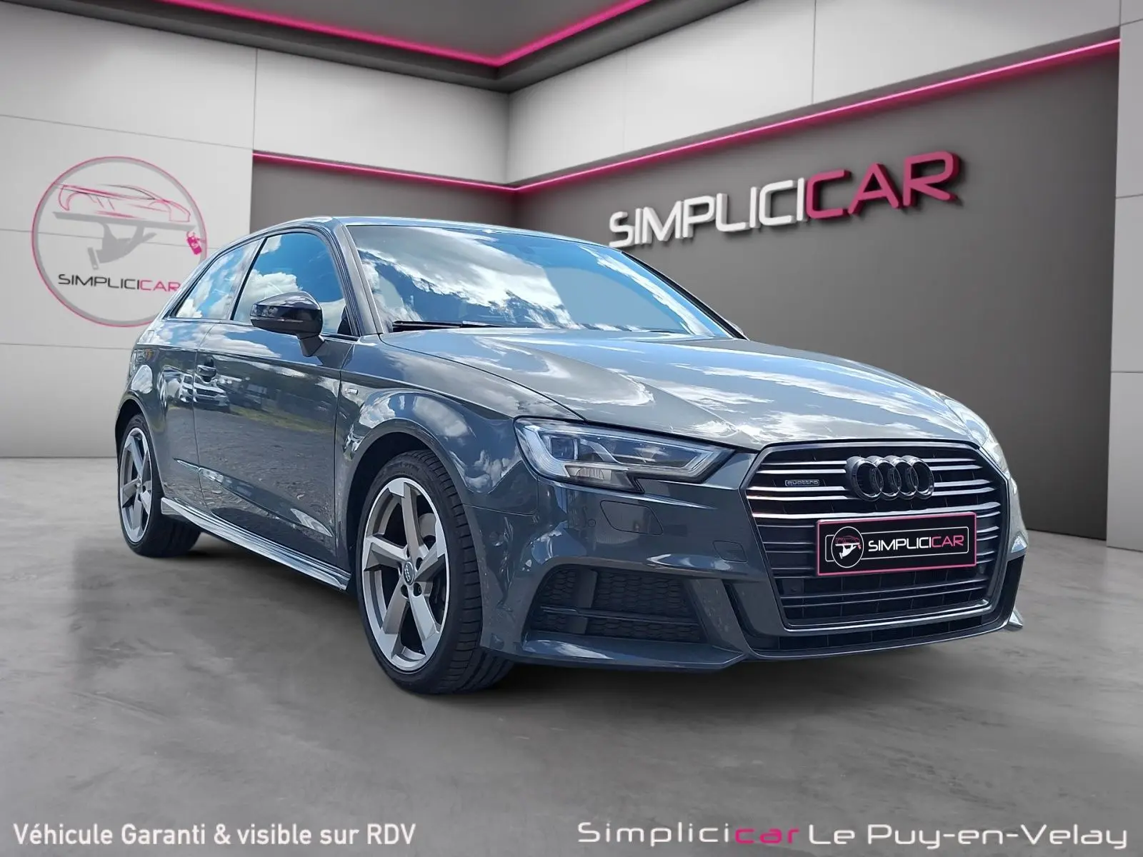 Audi A3 gris en 3/4 avant droit, avec calandre S Line et jantes alliage 18 pouces visibles en showroom.