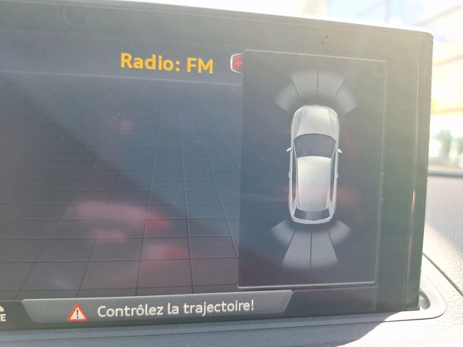 Écran intérieur affichant l'aide au stationnement avec vue aérienne du véhicule gris Audi A3 2017 en mode Park Assist.