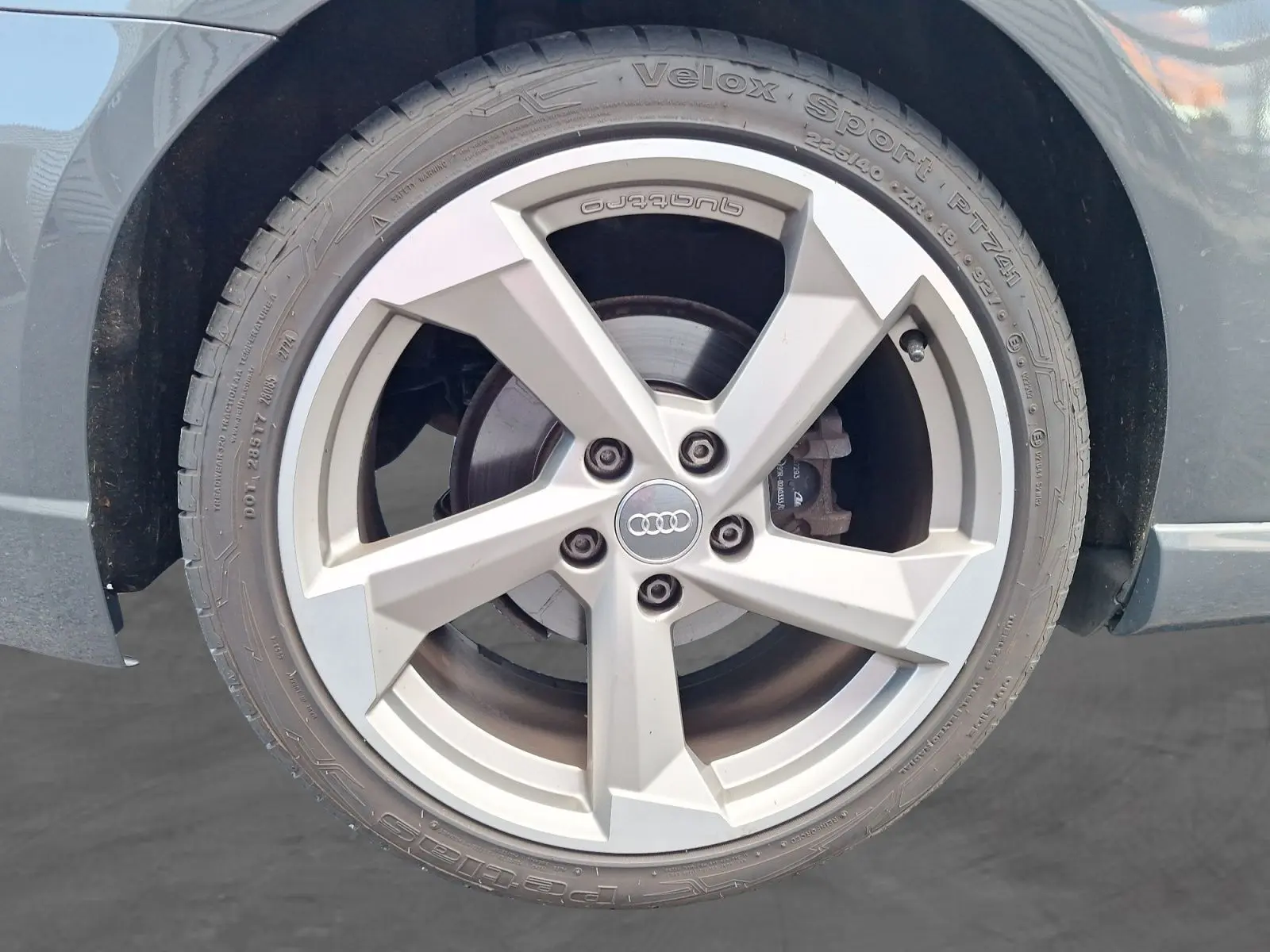 Gros plan sur la jante alliage 18 pouces grise avec logo Audi, sur la roue avant droite de l'Audi A3 gris.