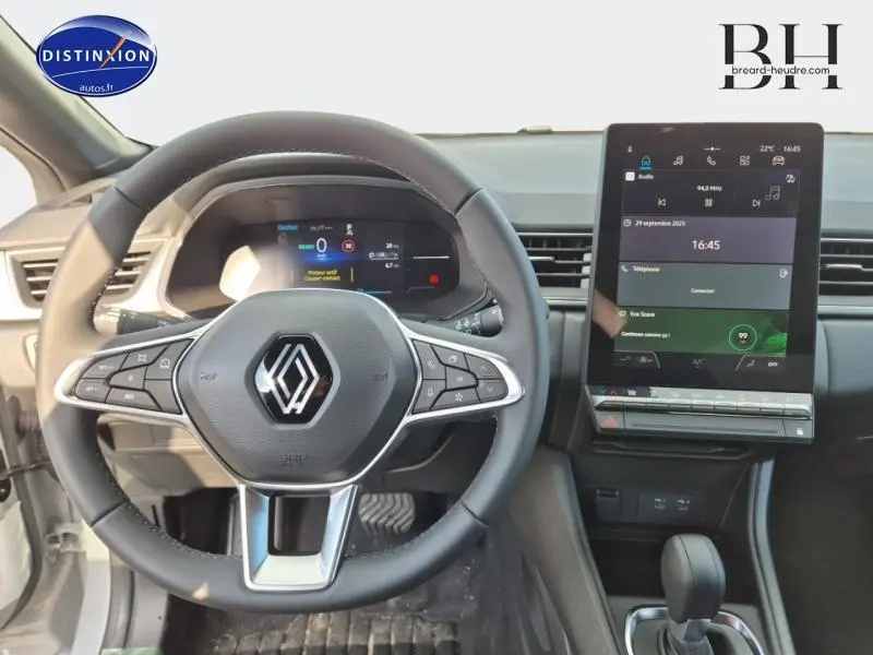 Vue intérieure centrée sur le volant multifonction et l'écran tactile vertical du Renault Captur gris 2025.