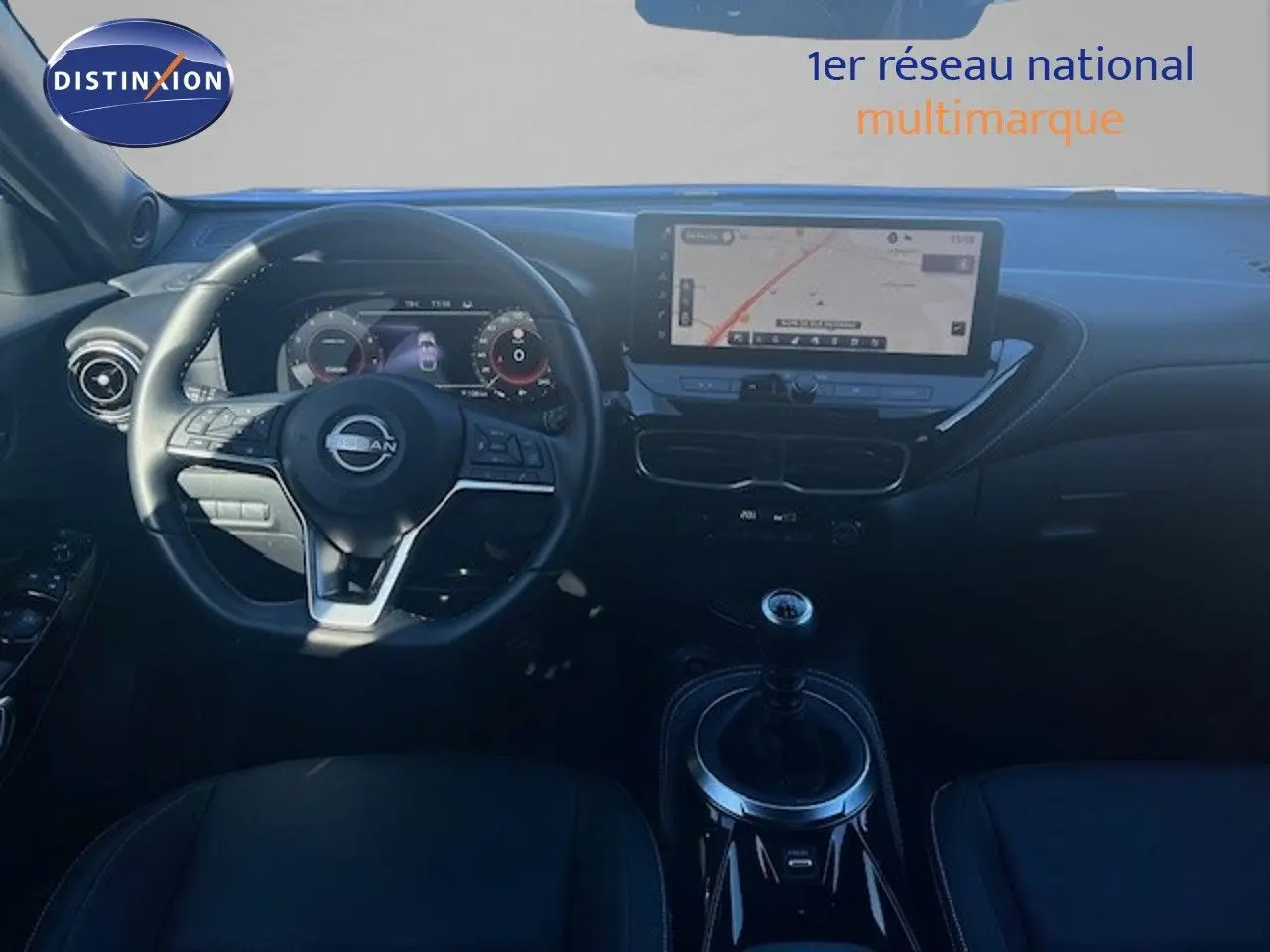 Vue intérieure frontale du tableau de bord du Nissan Juke 2025 avec volant multifonction et écran tactile de navigation.