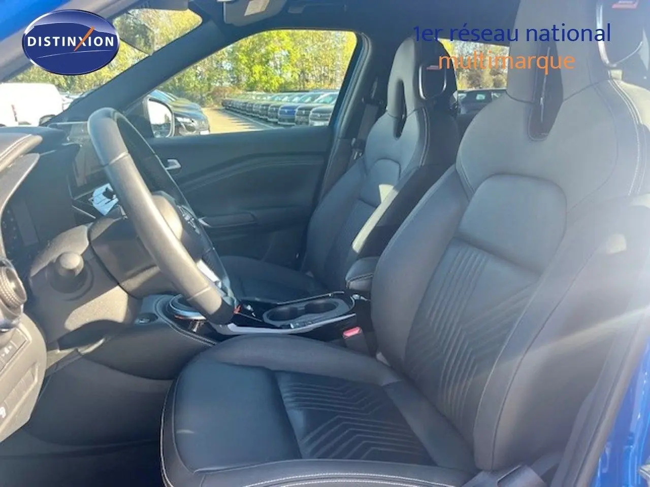 Vue intérieure côté conducteur du Nissan Juke 2025 bleu magnétique, sièges avant en cuir noir avec surpiqûres.