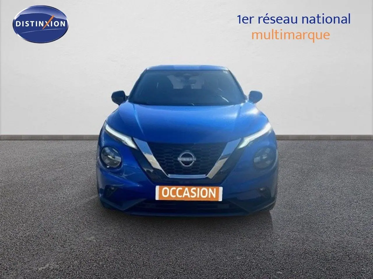 Vue frontale d'un Nissan Juke 2025 bleu magnétique métal avec calandre chromée et phares LED allumés.