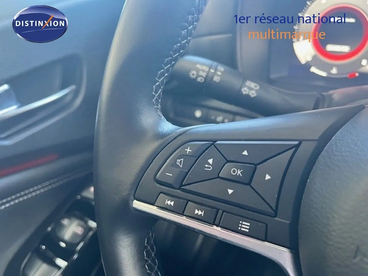 Gros plan sur le volant cuir noir du Nissan Juke 2025, avec commandes multifonctions et tableau de bord partiellement visible.