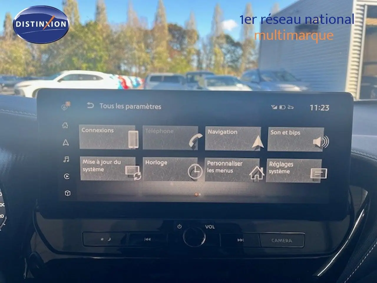 Vue avant intérieure sur l’écran tactile du Nissan Juke bleu magnétique métal 2025 avec commandes de volume et caméra.