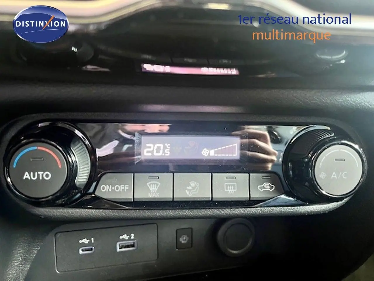 Détail de la console de climatisation automatique du Nissan Juke bleu magnétique, avec affichage digital et commandes rotatives.