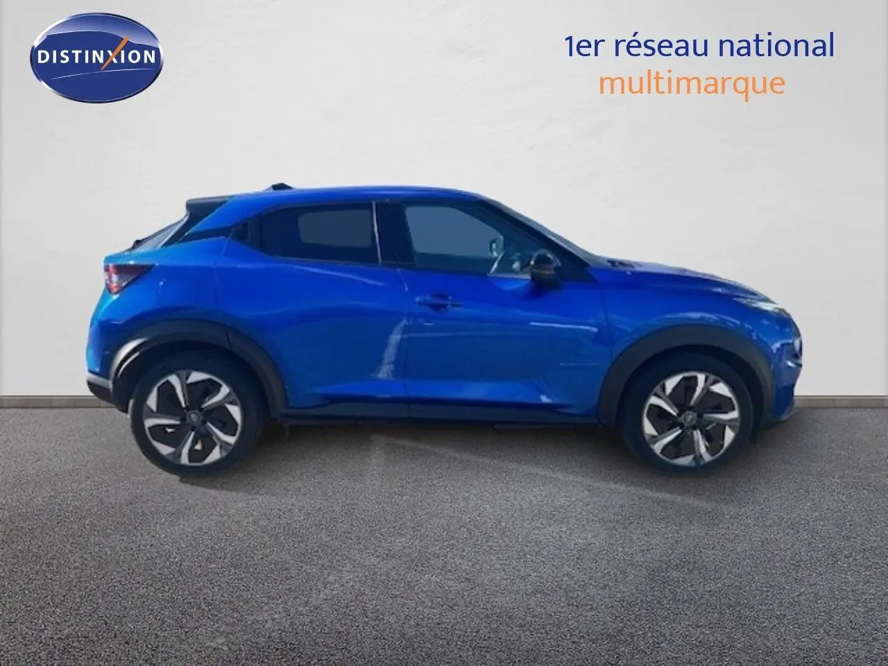 Vue de profil côté gauche d'un Nissan Juke 2025 bleu magnétique métal avec jantes distinctives et lignes modernes.