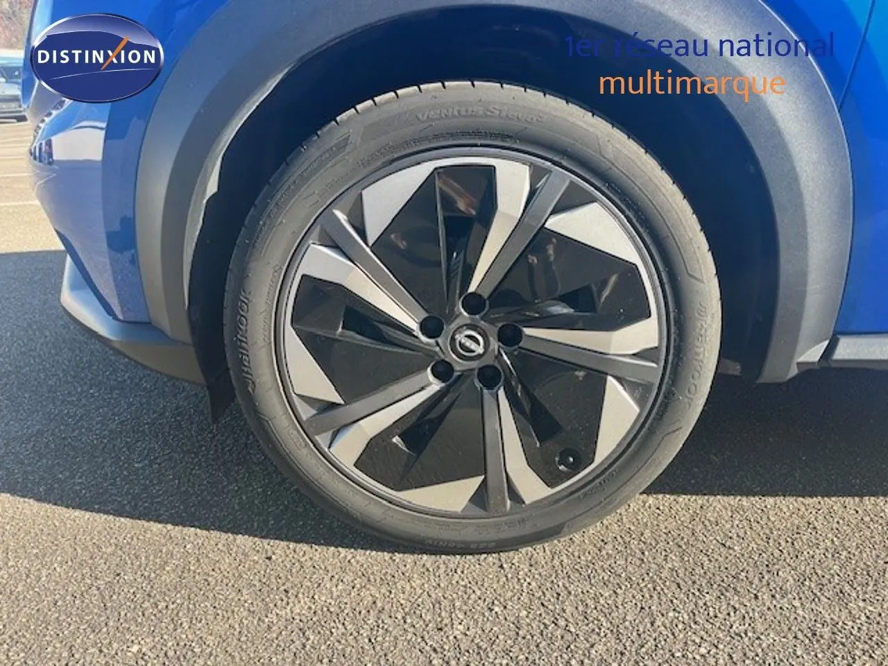 Gros plan sur la roue avant gauche du Nissan Juke 2025 bleu magnétique métal avec jante noire et argentée au design moderne.