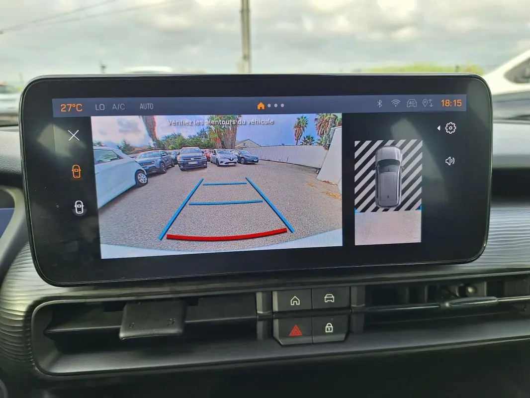 Vue intérieure sur l'écran tactile du Jeep Avenger blanc montrant la caméra de recul et l'aide au stationnement.