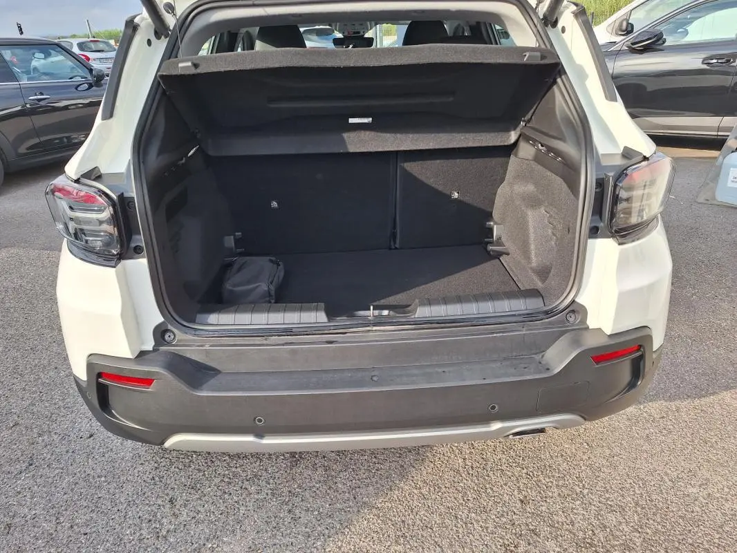 Coffre ouvert vu de l'arrière d'un Jeep Avenger blanc 2025 avec feux arrière LED et pare-chocs noir.