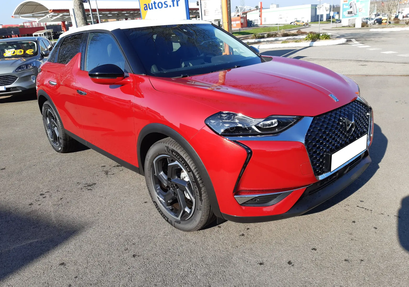 DS3 Crossback rouge métal avec toit blanc, vue 3/4 avant droit mettant en valeur la calandre distinctive et les jantes biton.
