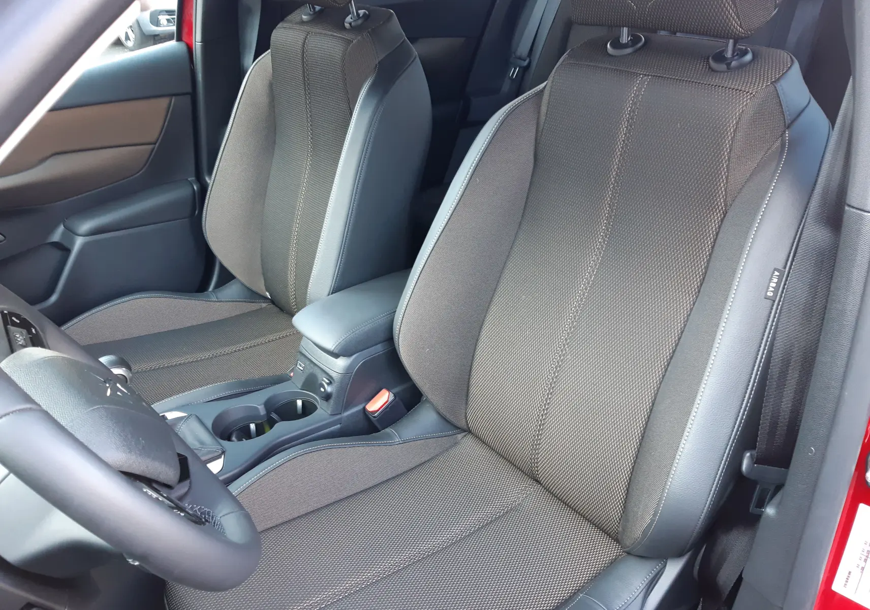 Vue rapprochée des sièges avant en tissu et cuir noir du DS3 Crossback rouge métal, côté conducteur ouvert.