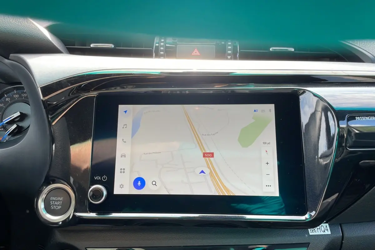 Tableau de bord du Toyota Hilux 2025 avec écran tactile de navigation et bouton start/stop visible.