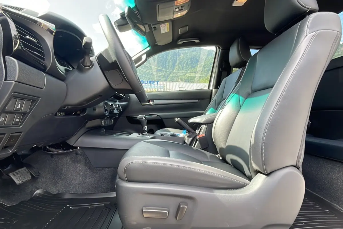 Intérieur du Toyota Hilux Invincible 2025 vu côté conducteur, sièges cuir gris et tableau de bord moderne.